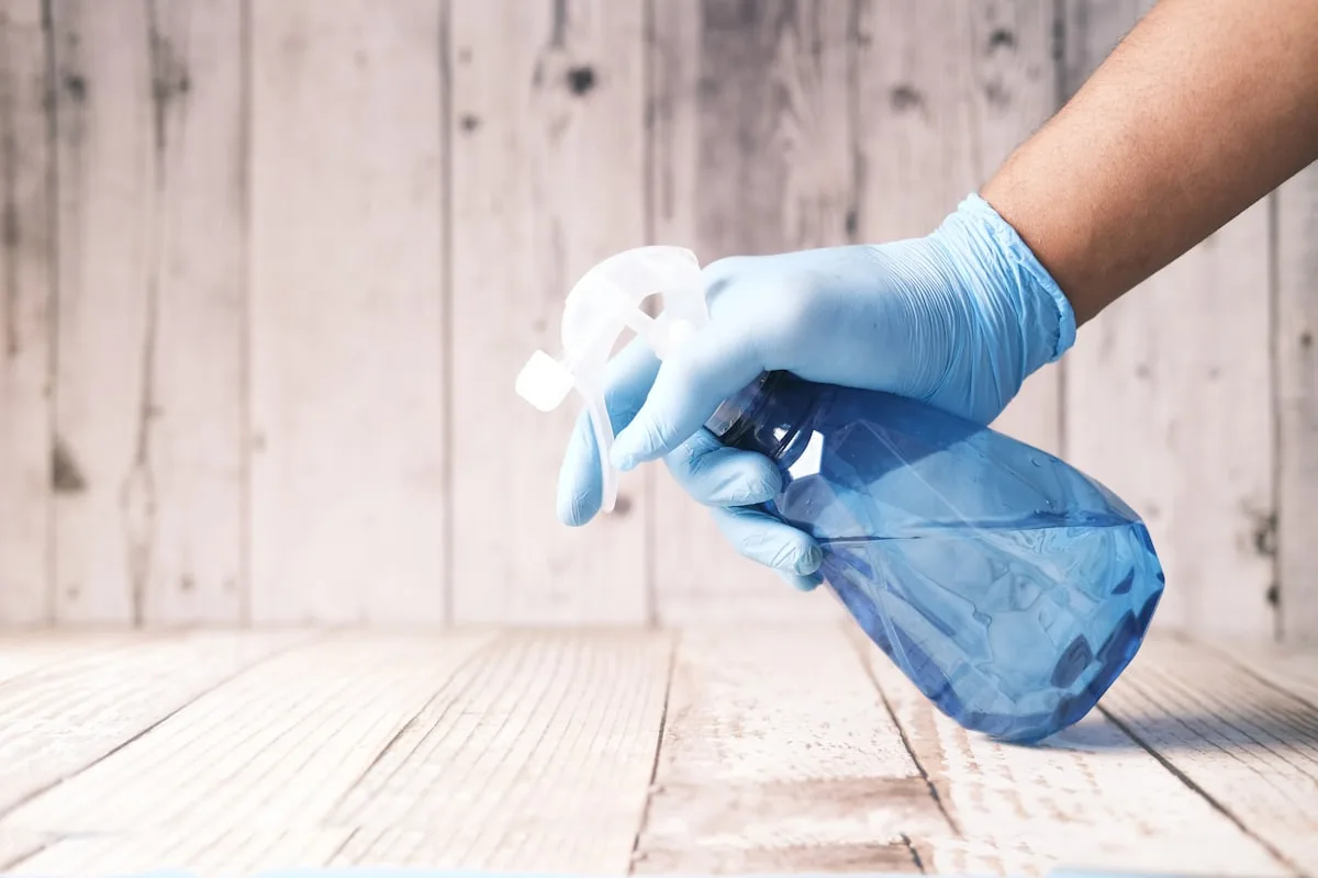 Gloved hand holding a spray bottle before starting a clean