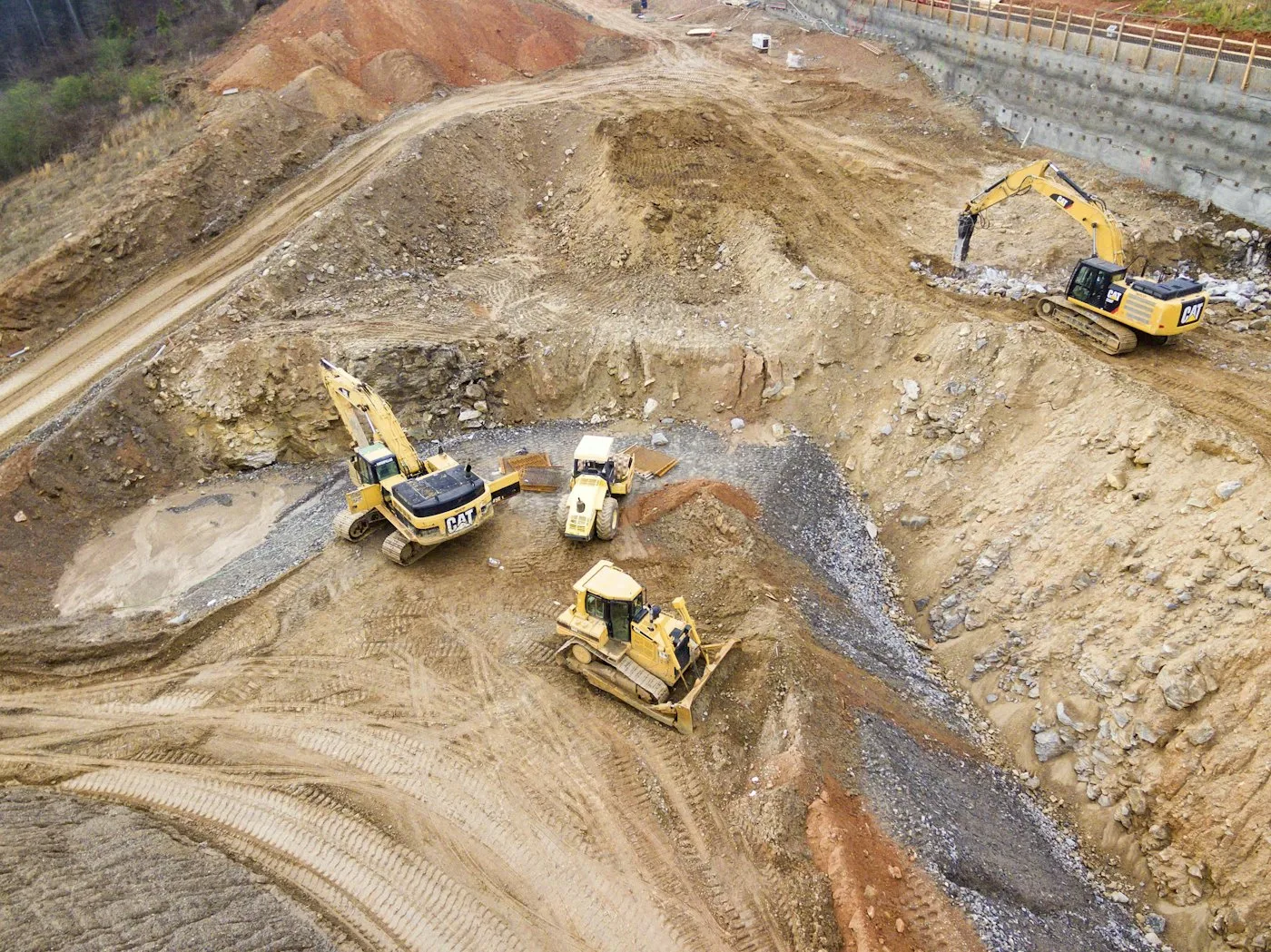 Aerial view of excavators and a dozer shaping earth on a job site