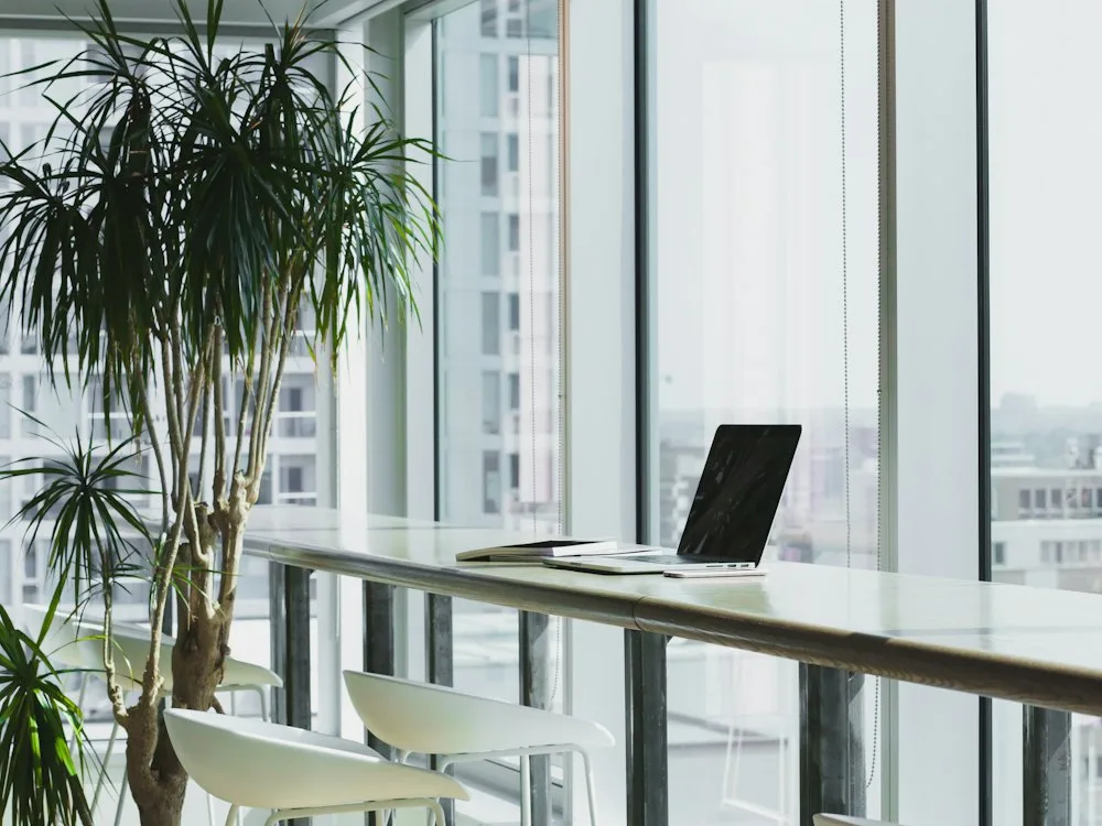 Laptop on a bright office worktop overlooking a city