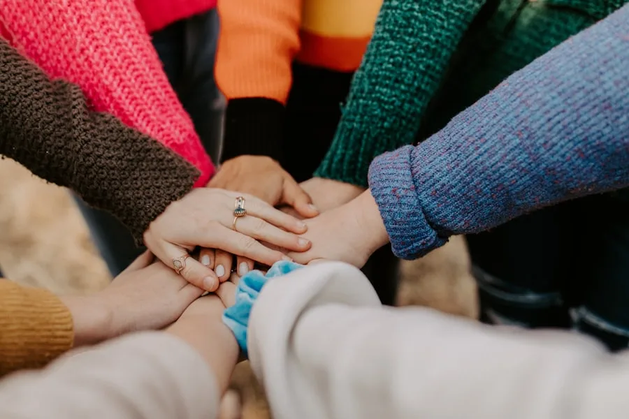 A group of volunteers placing their hands together in a circle