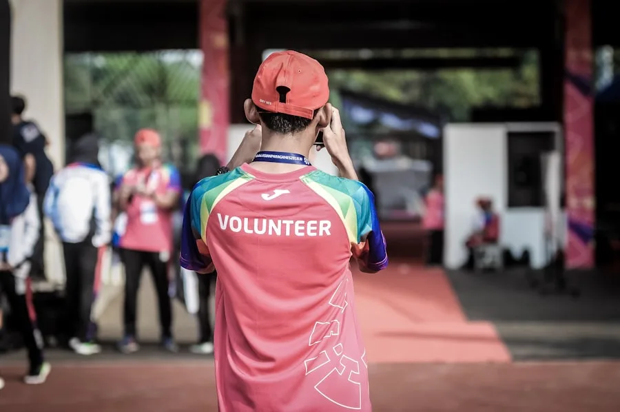 Volunteer in a bright team shirt standing at an outdoor service site
