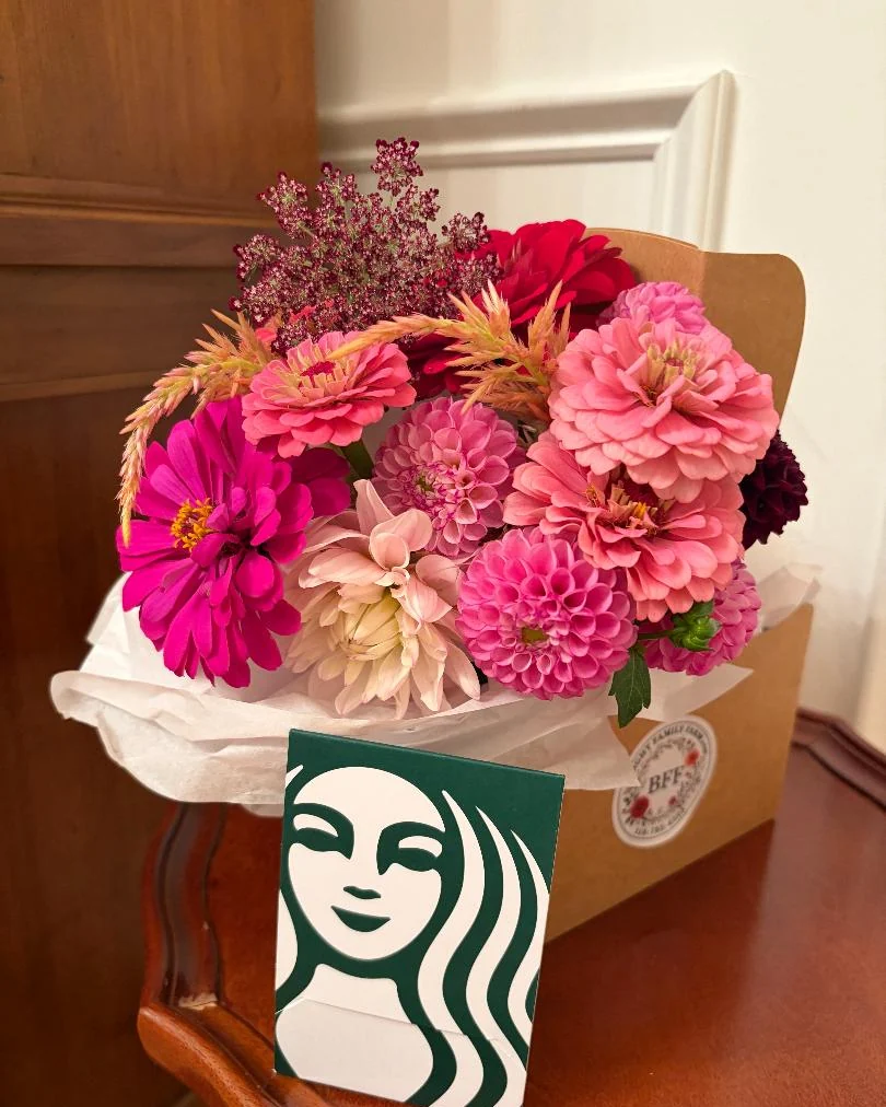A kraft carrier filled with pink zinnias and dahlias, a Starbucks gift card leaning against it
