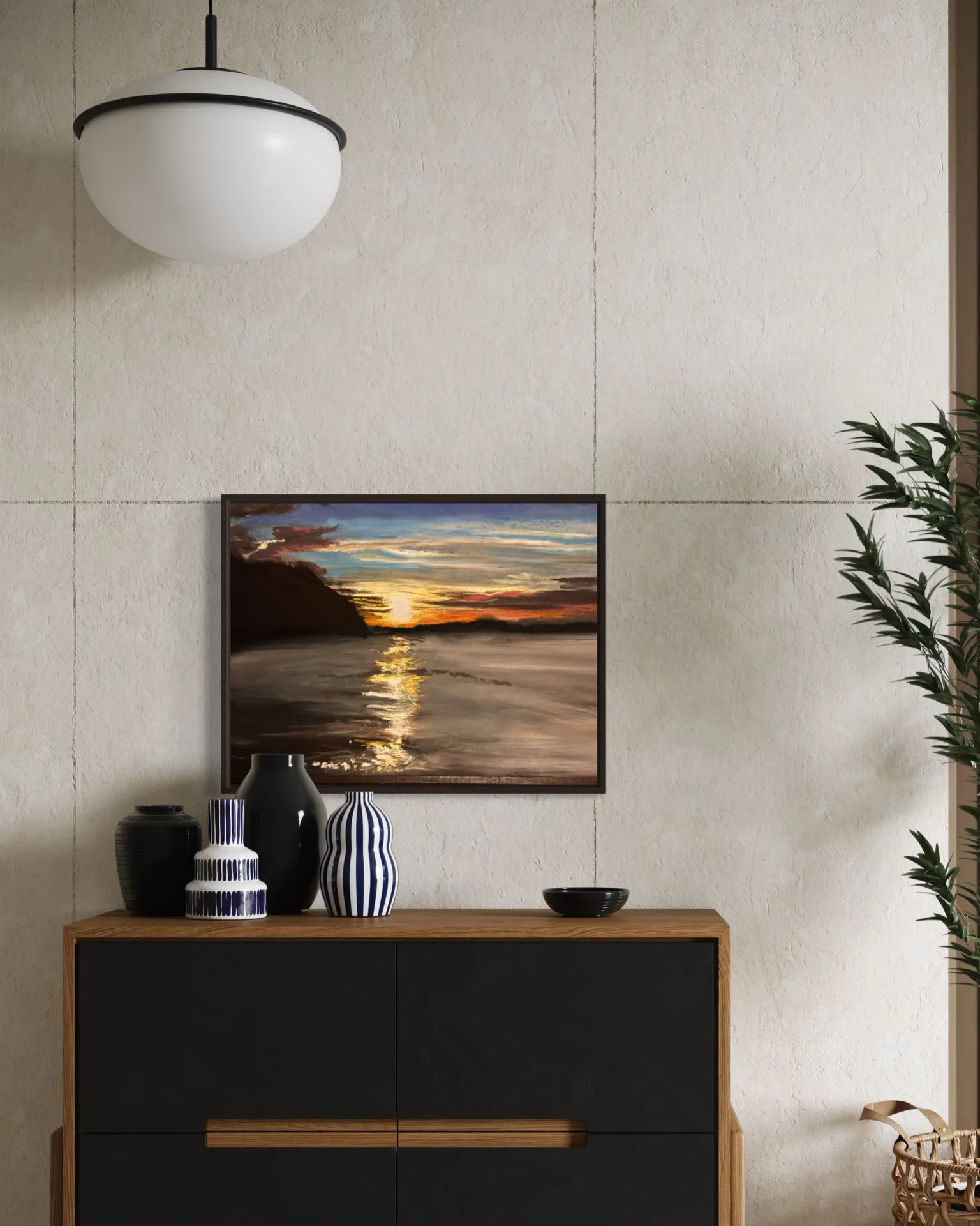 The framed sunset pastel hung on a pale plaster wall above a black credenza with ceramic vases