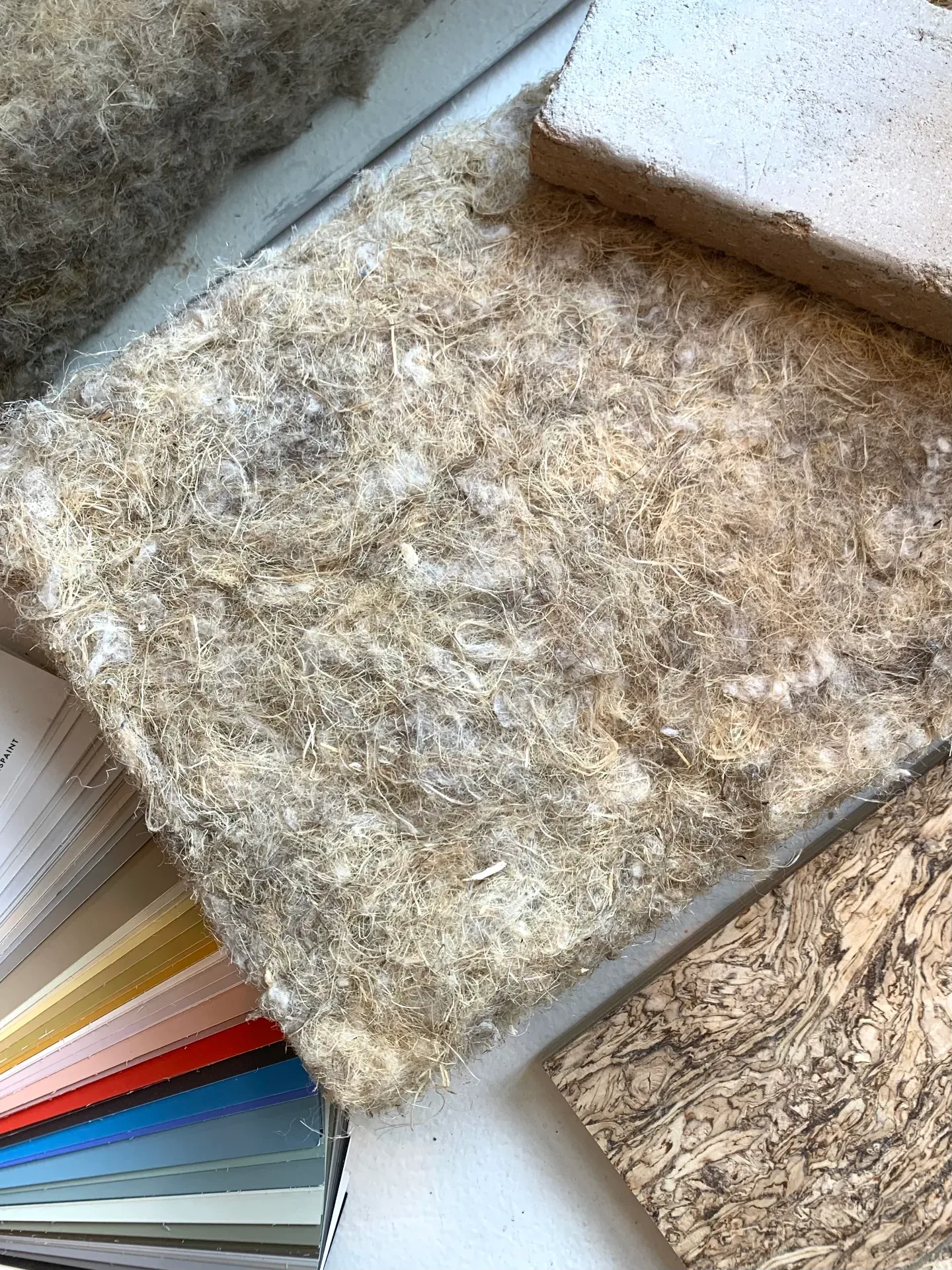 Two hands spreading a fan of fabric and finish samples across a work table