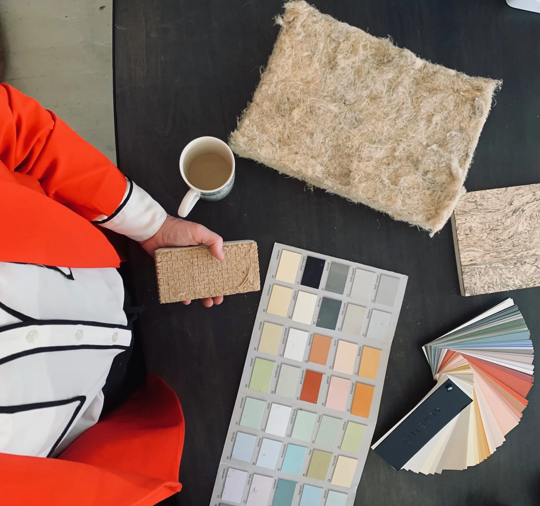 A materials consultation in progress, showing paint samples, insulation materials, and building documentation on a work surface