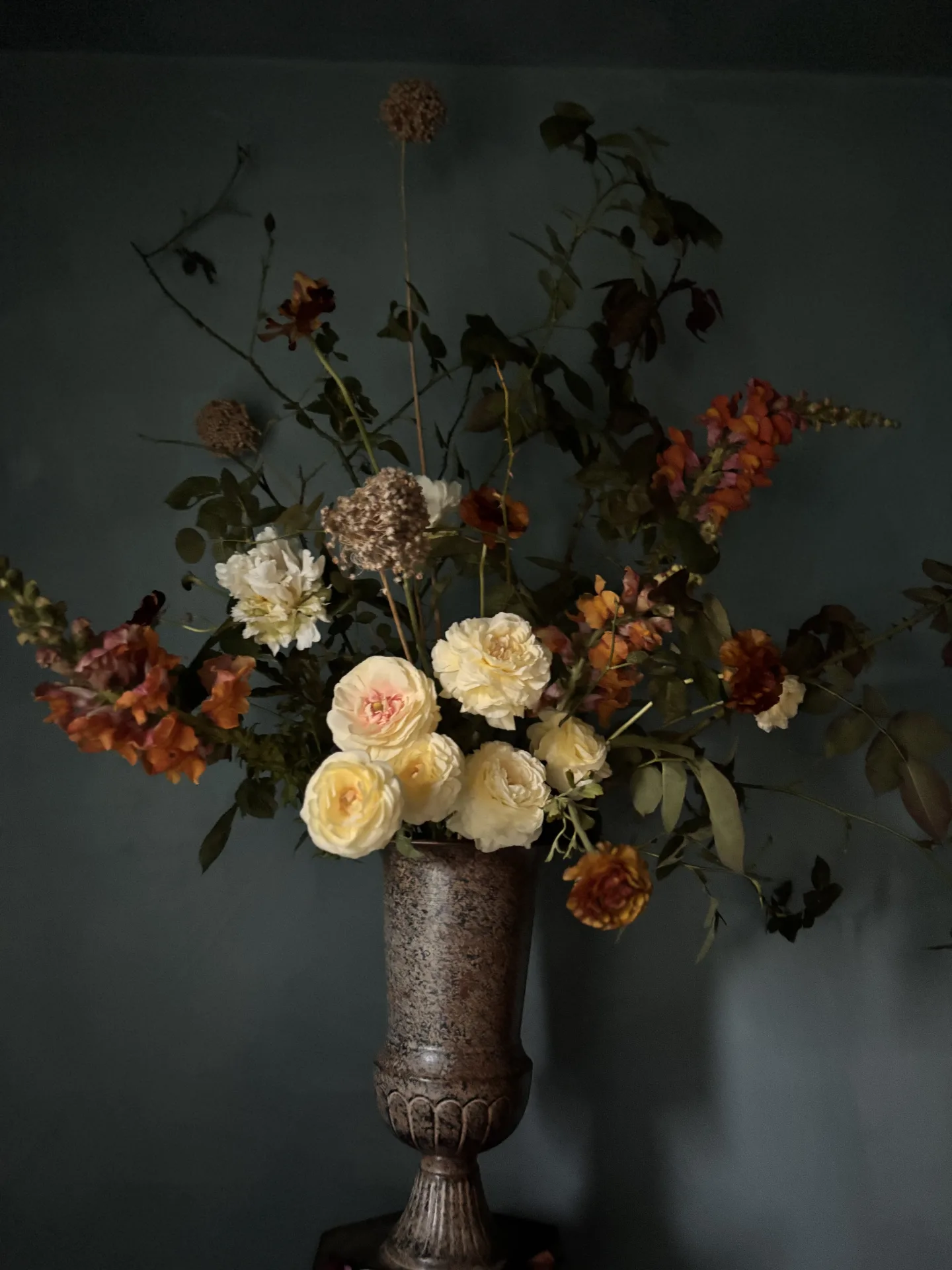 A Dutch still-life style arrangement of flowers in a handmade pottery urn on a wood table