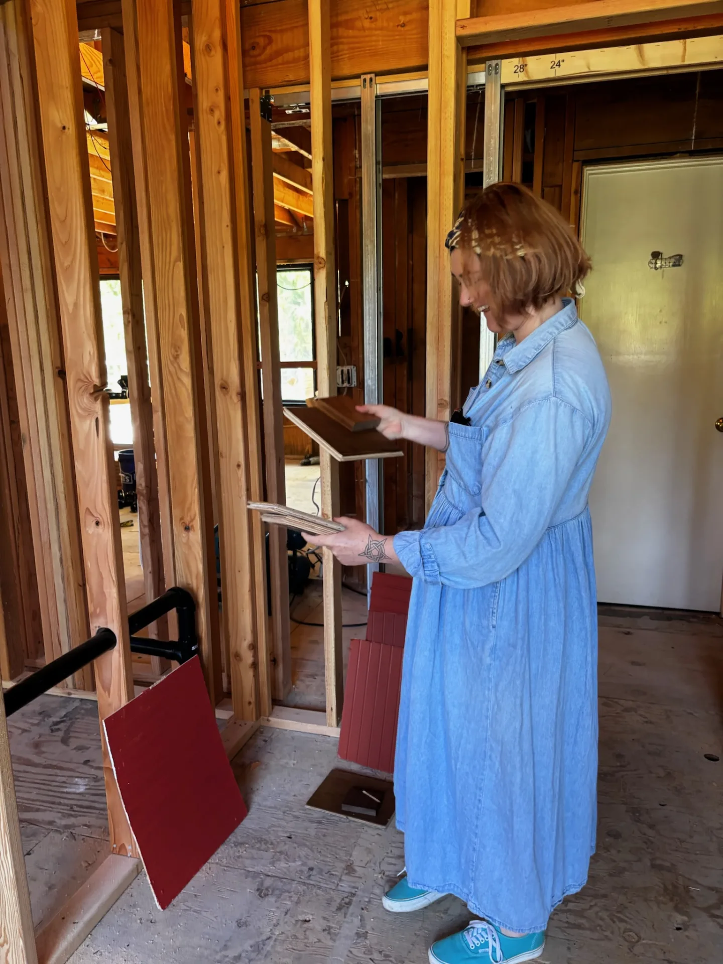 Woman in a chambray dress looking at wood and flooring samples in a room under renovation
