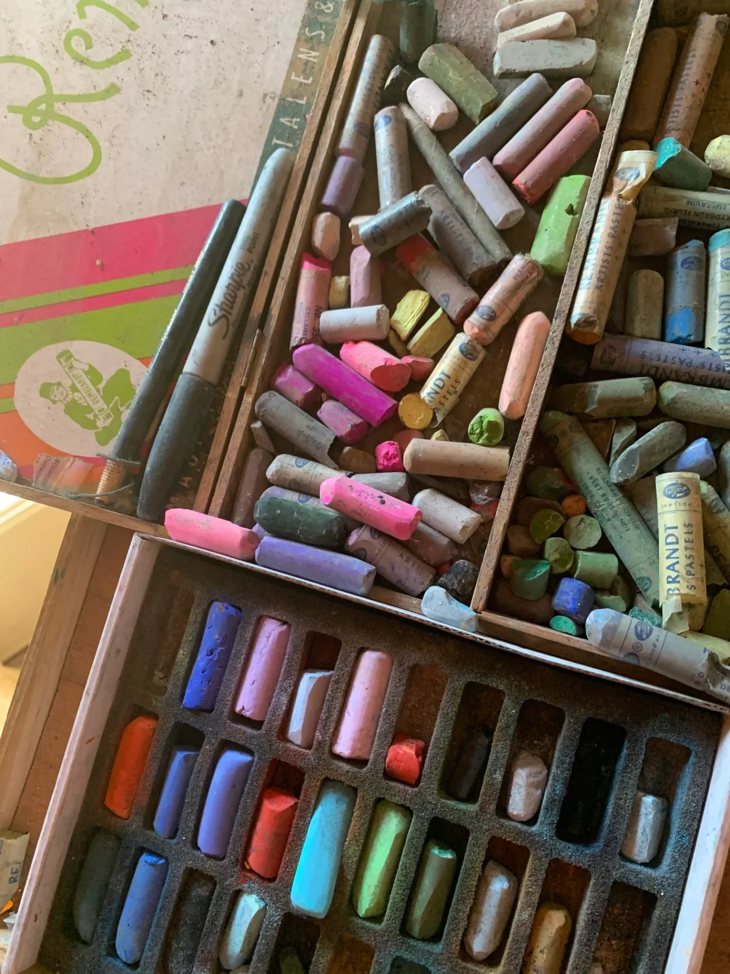 Close-up of soft pastel sticks in a studio work box, showing a wide range of vibrant colours including pinks, blues, greens, and earth tones