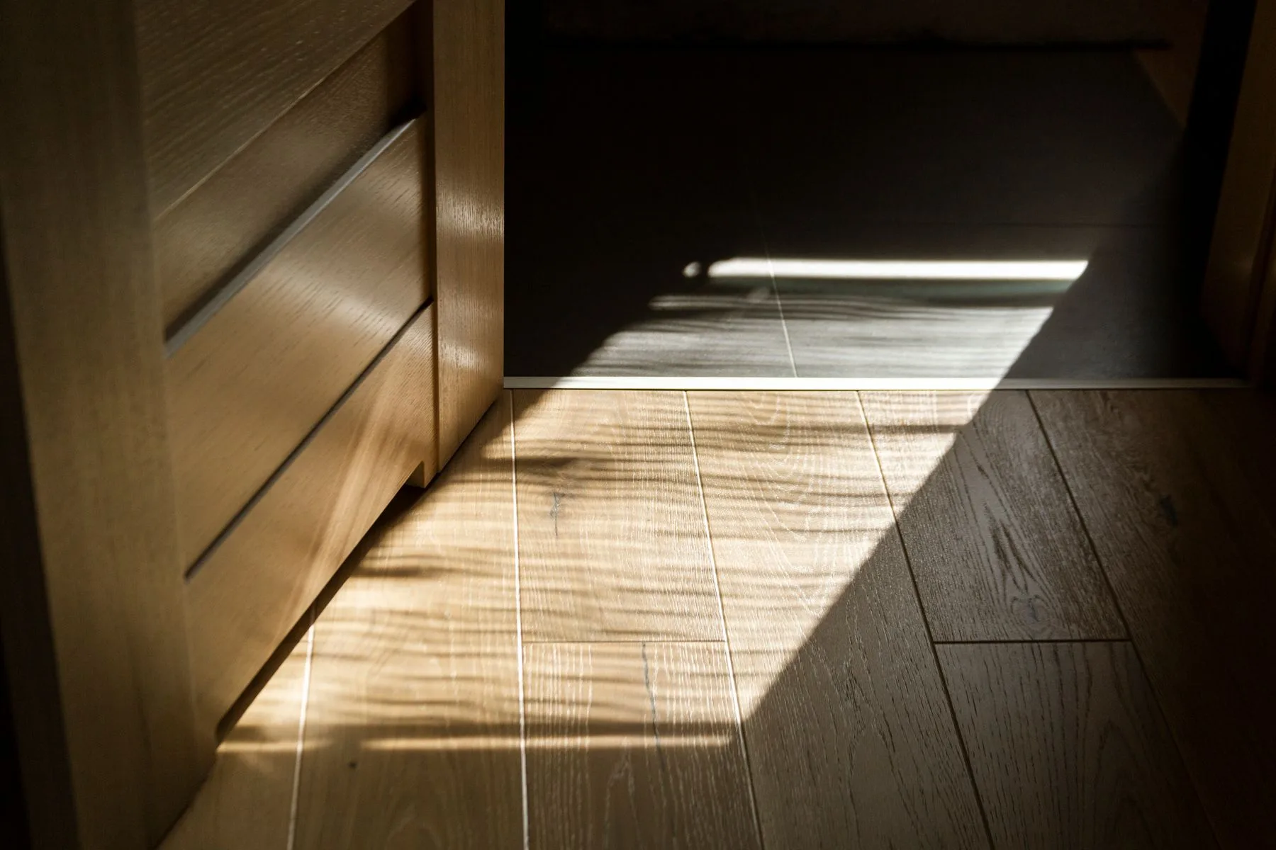 Wide oak plank flooring in raking sunlight, the grain lifted by a natural oil finish