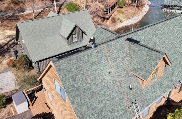 Aerial view of a lake home with new green architectural shingles