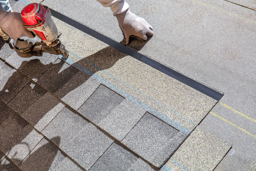 Roofer nailing new asphalt shingles