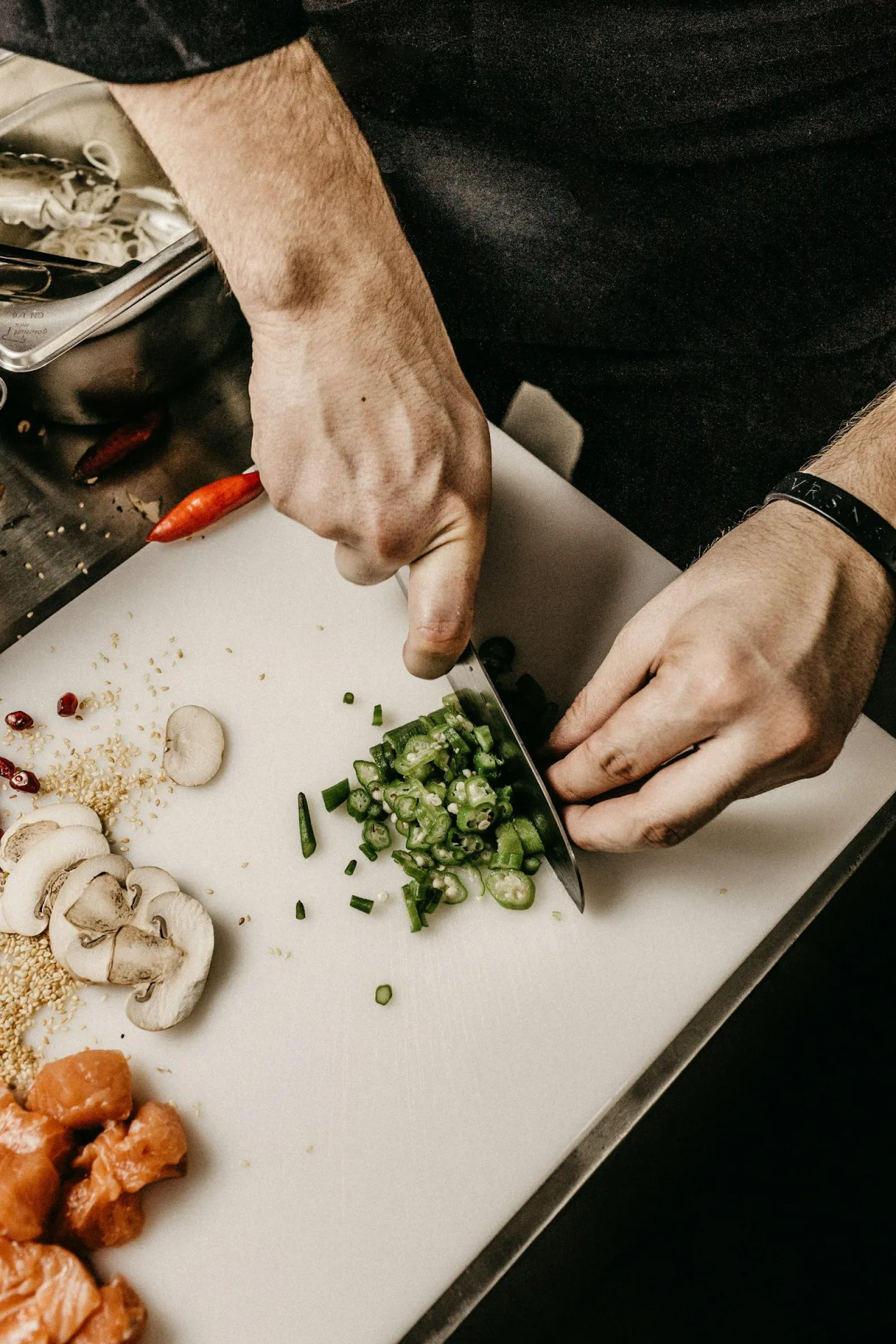 A chef slicing fresh vegetables beside salmon and mushrooms