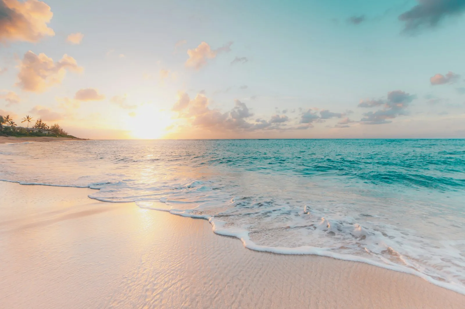 Soft waves rolling onto the sand under a golden sunset