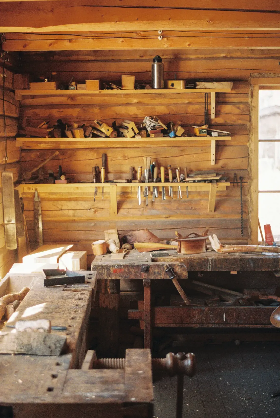 A workbench with hand tools racked on the wall above it