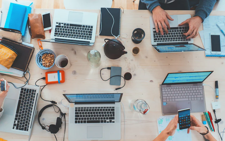 Laptops, phones and accessories laid out on a desk from above