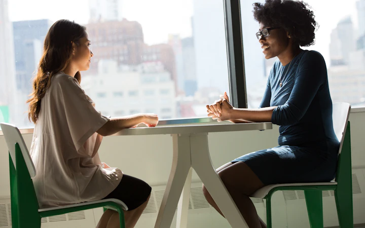 Two colleagues in a quarterly review conversation beside a window
