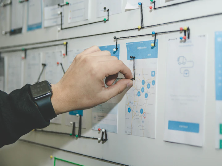 A hand arranging planning cards on a wall during a strategy session