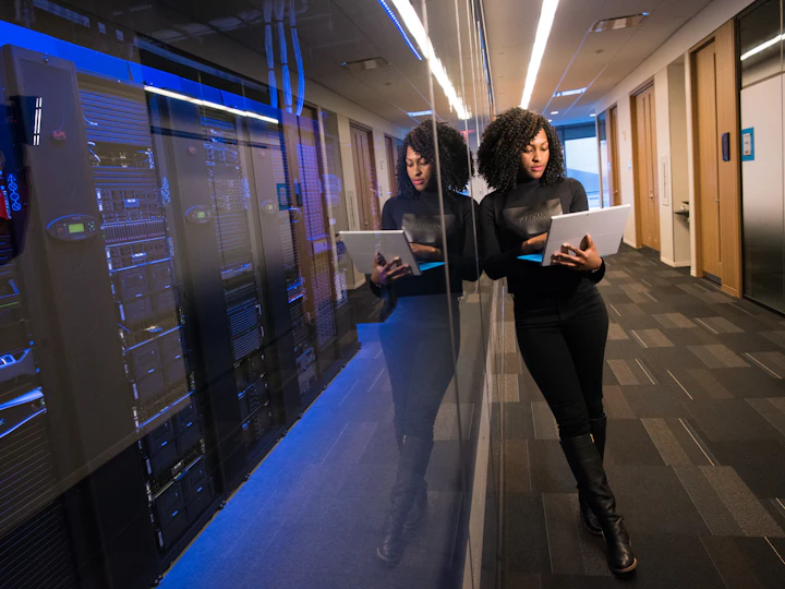 An engineer with a tablet walking the aisle of a lit server room