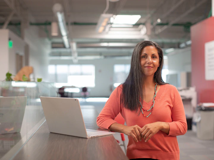 A support engineer standing with a laptop in an open-plan office