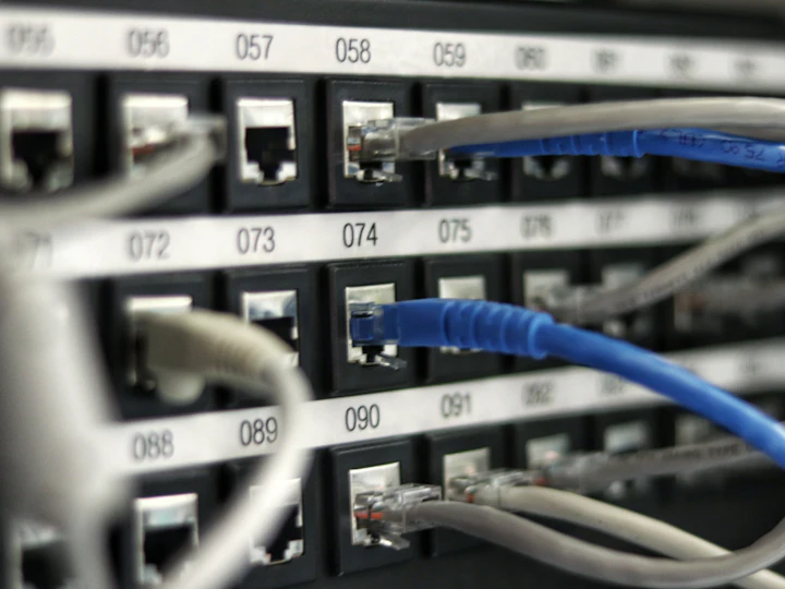Blue and grey network cables patched into a numbered switch panel