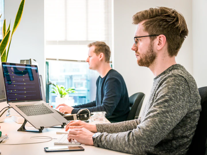 Two developers writing code at adjacent desks