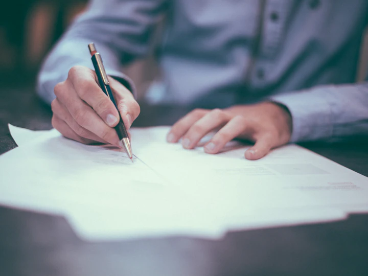 A person signing a printed document with a fountain pen