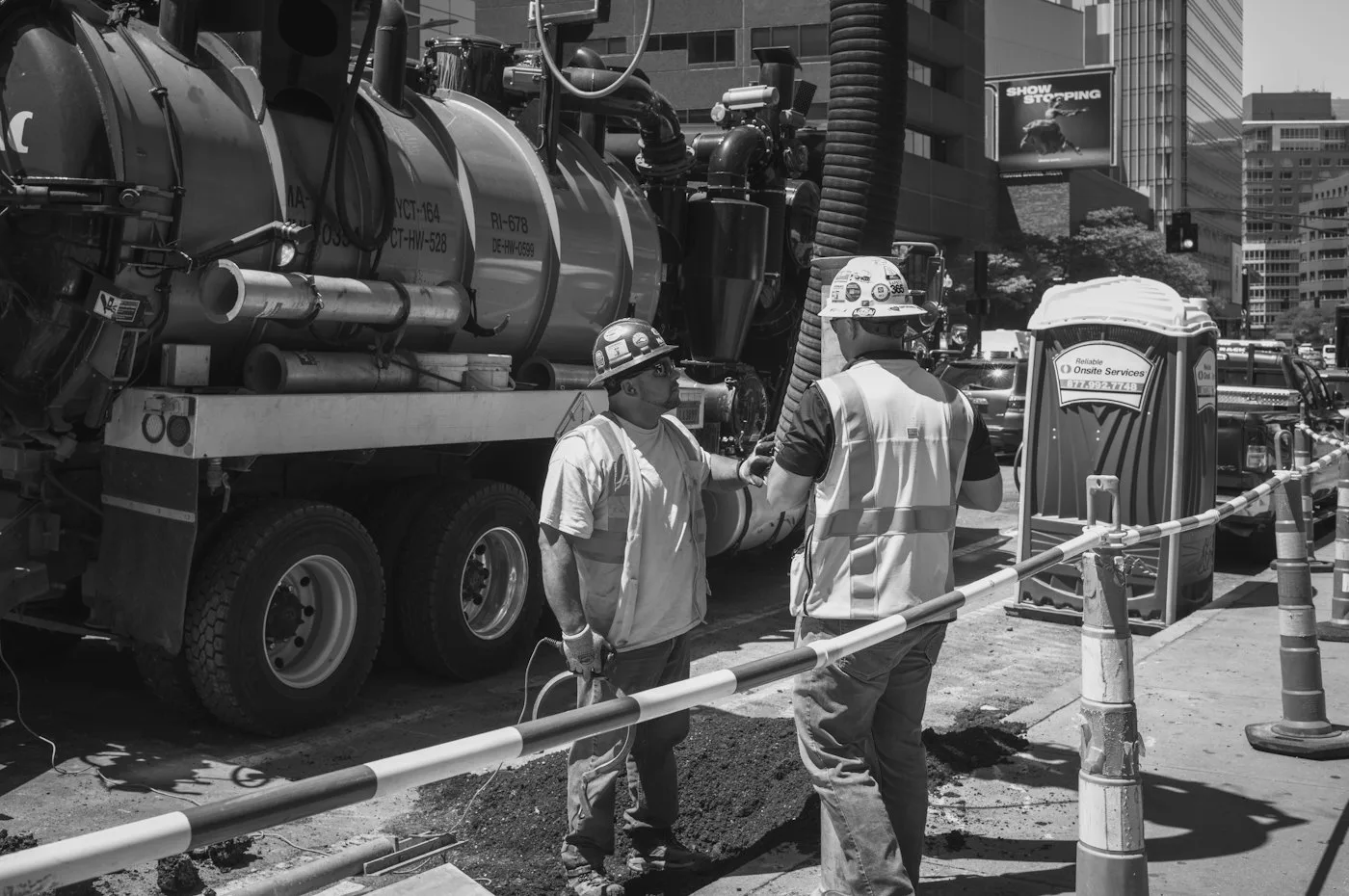 Utility crew in hard hats talking beside a vacuum excavation truck