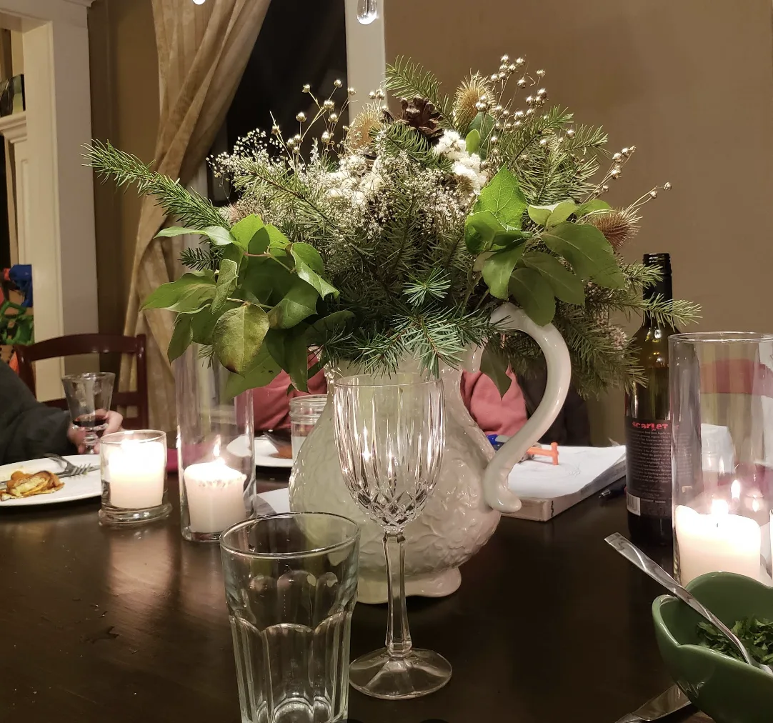 A candlelit table set with fresh garden flowers in a white pitcher, ready to welcome guests.