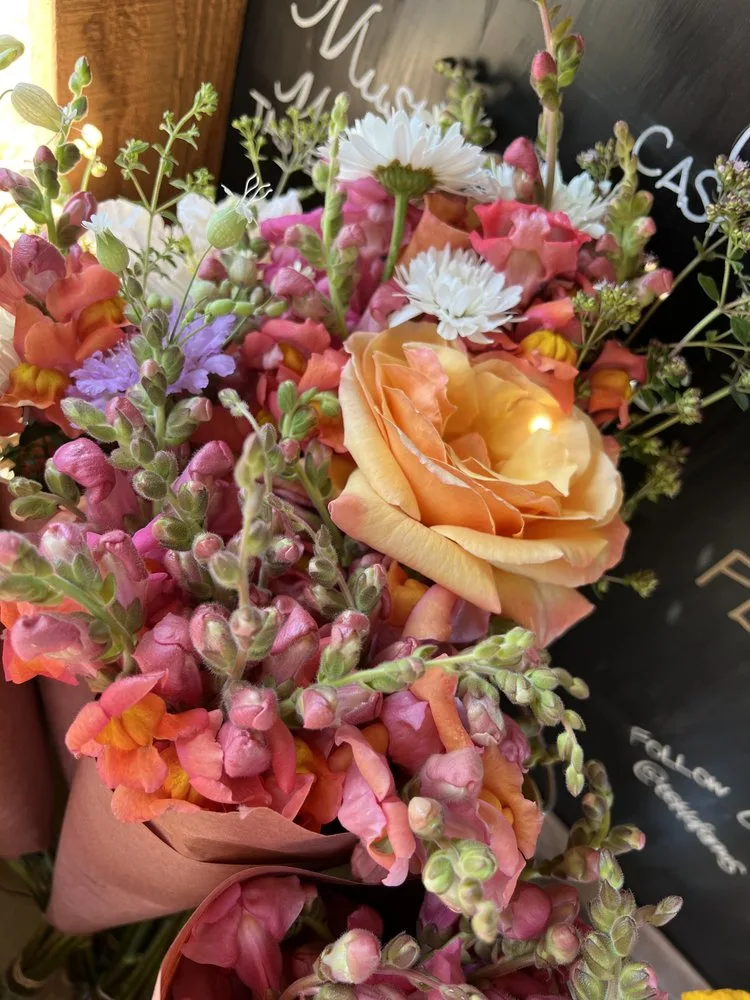 Bouquets of snapdragons and roses at the farm stand by the chalkboard