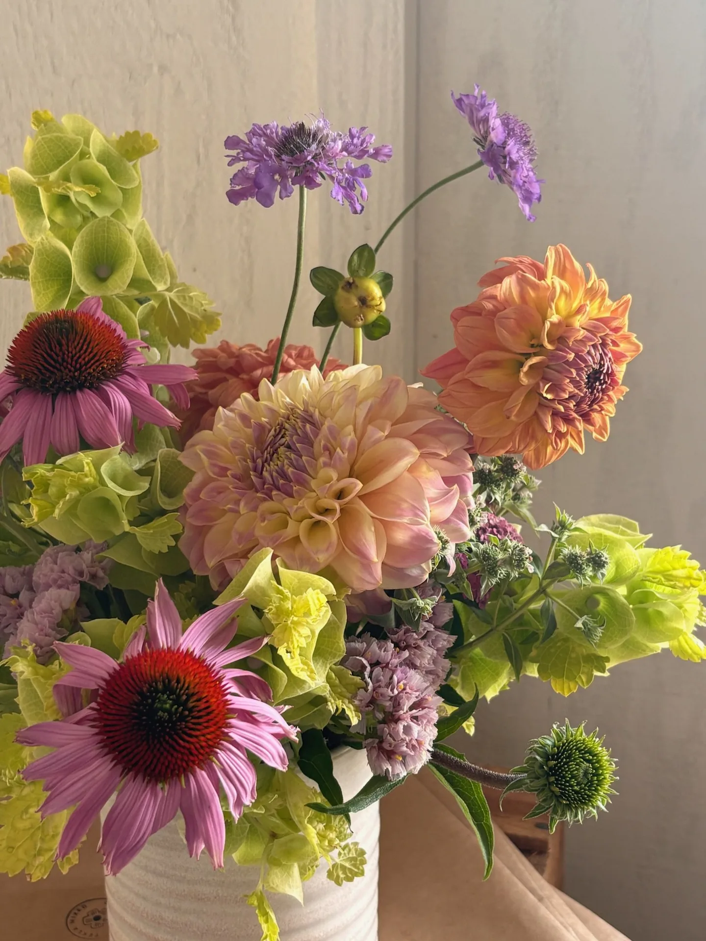 A premium arrangement of coneflowers, dahlias and scabiosa in a ceramic vessel