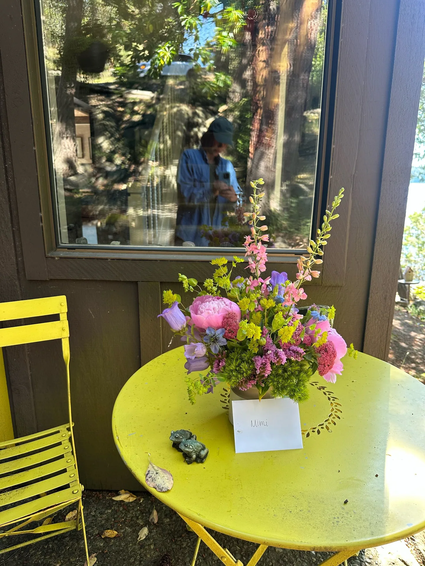 A wrapped bouquet of dahlias on a yellow bistro table by the window