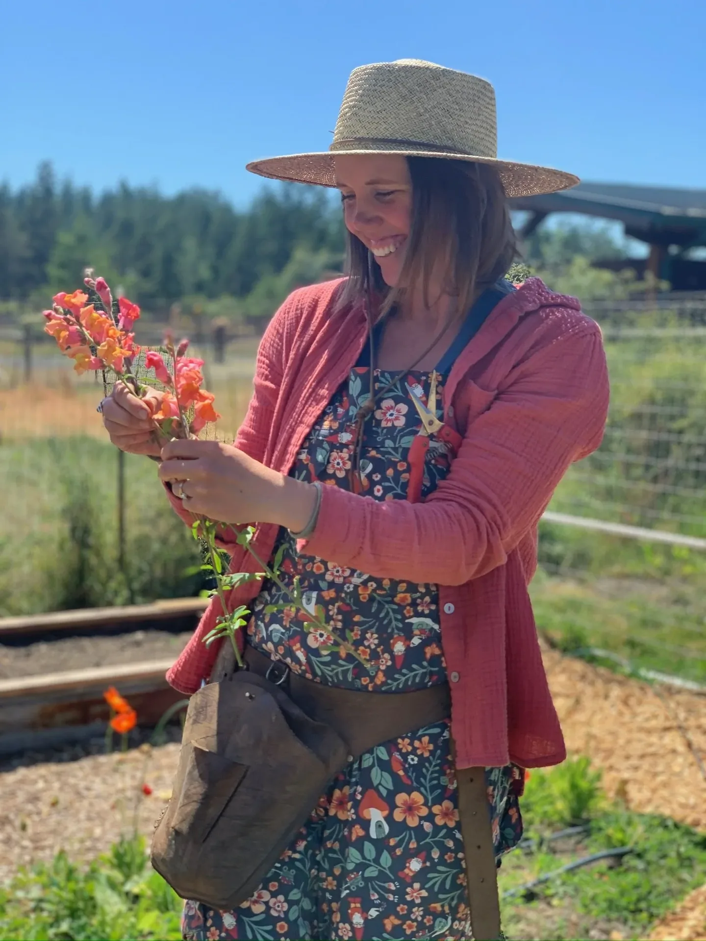 Laura in a sun hat holding a coral snapdragon in the flower field