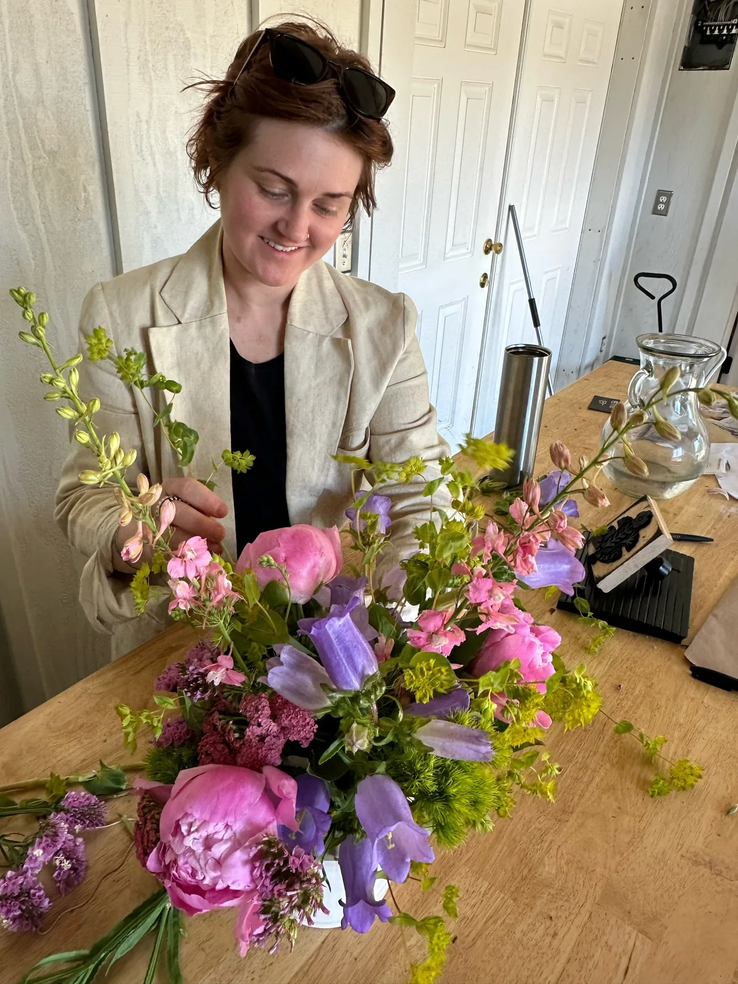 Designer Whitney Page arranging a compote of pink and burgundy blooms