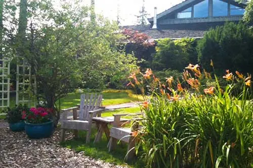 Wooden garden chairs among day lilies near the lodge