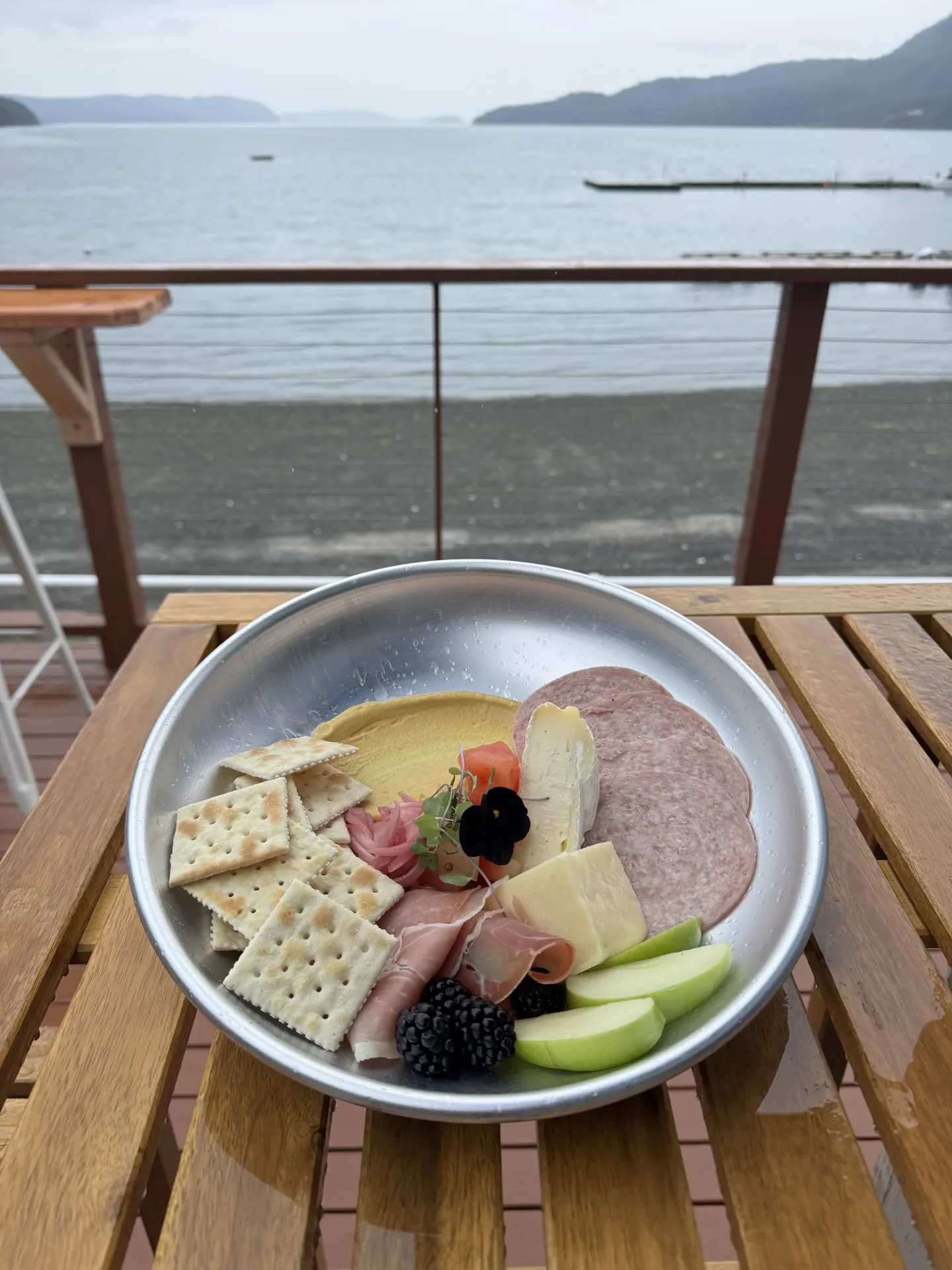 Meat and cheese board with prosciutto, brie, market fruit and saltines