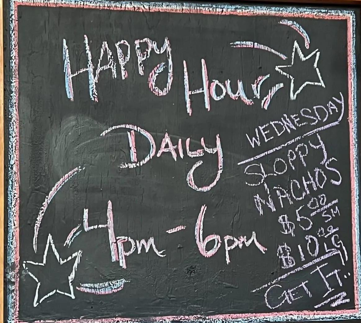 Chalkboard reading Happy Hour Daily 4pm to 6pm, Wednesday sloppy nachos