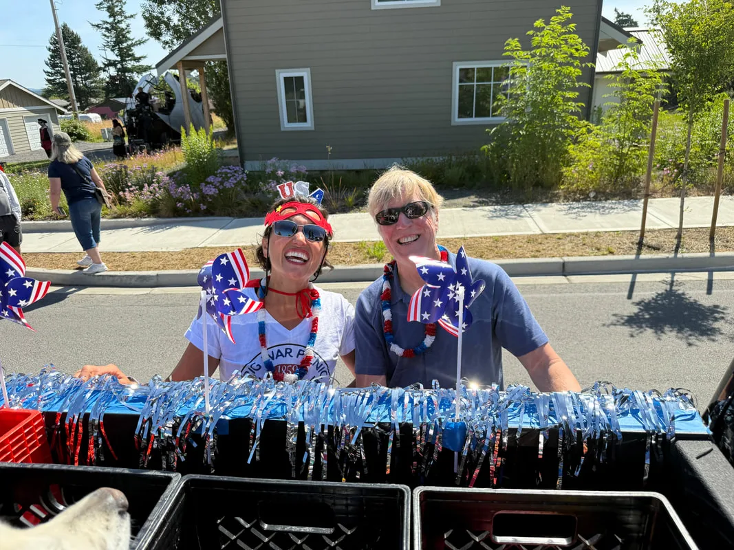 Two smiling food bank volunteers in red, white and blue at a summer parade